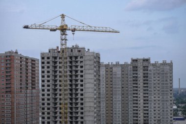 İnşaat sırasında çok aşamalı inşaat ve sarı bir vinç. Tasarım için endüstriyel arkaplan.