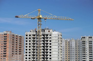 İnşaat sırasında çok aşamalı inşaat ve sarı bir vinç. Tasarım için endüstriyel arkaplan.