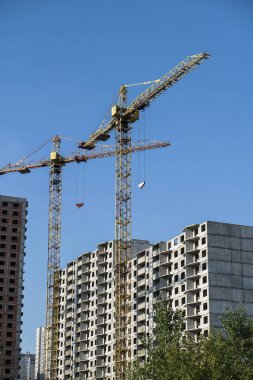 İnşaat sırasında çok aşamalı inşaat ve sarı bir vinç. Tasarım için endüstriyel arkaplan.