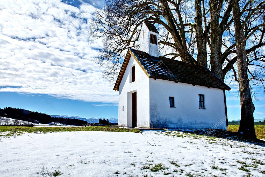 Beautiful winter wonderland mountain scenery in the Alps with small chapel near Schwangau (Bavaria, Germany)