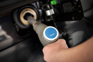 Hand filling tank with diesel at a self service gas station clipart