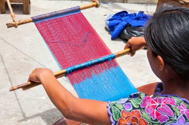 San Lorenzo Zinacantan, Mexico - May 10, 2014: Indigenous Tzotzil women weaving a traditional Huipil at the loom. San Lorenzo Zinacantan is a small village in the southern part of the Central Chiapas highlands in the Mexican state of Chiapas. clipart