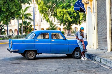 Havana, Küba - 12 Aralık 2016: Sokak sahne Eski Havana'da. Kübalı bir adam onun Amerikan klasik otomobil ve yasaktır puro yanında ayakta