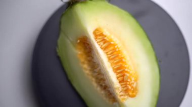 Çekirdekle dolu çeyrek dilim kavun dönüyor, yukarıdan çekiliyor. Çekim meyvelerin doğal dokusunu, tazeliğini ve tropikal cazibesini vurguluyor.