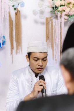 Geleneksel beyaz giysili ve siyah şapkalı Asyalı bir adam basitliği, inancı ve kültürel mirası simgeliyor. İslami gelenekleri, dini etkinlikleri, düğünleri ve kültürleri resmetmek için mükemmel. 