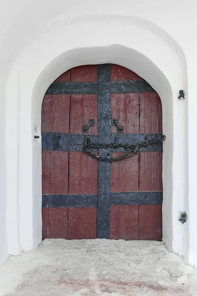 Puerta de madera antigua con asas de hierro forjado y cadena sobre fondo de pared encalado . — Foto de Stock