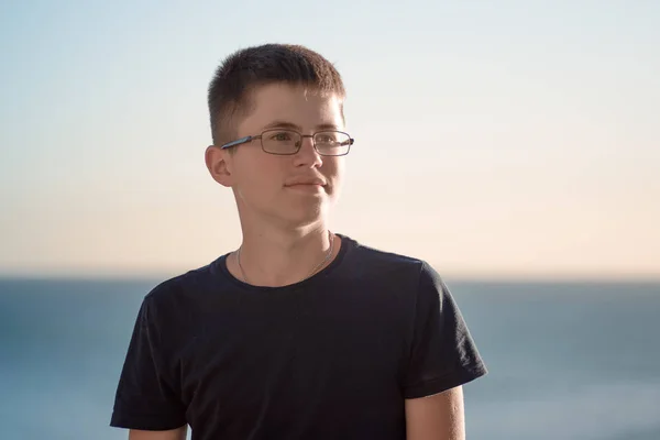 Portret poziomy wesoły nastolatek chłopak w okularach przeciw morze o zachodzie słońca. — Zdjęcie stockowe