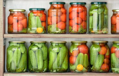 Glass jars with home canned vegetables standing in rows on wooden shelves. clipart