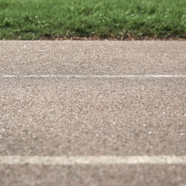 緑の草を背景にマーキングとテクスチャ舗装道路。写真の一部がぼやけている. — ストック写真