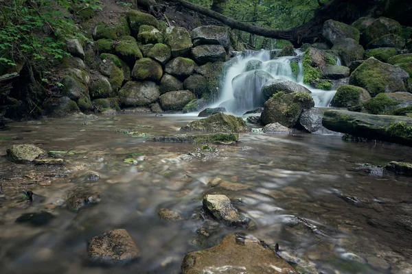 Old ruined water mill. Falling water at long exposure on Mill Creek in the green forest.