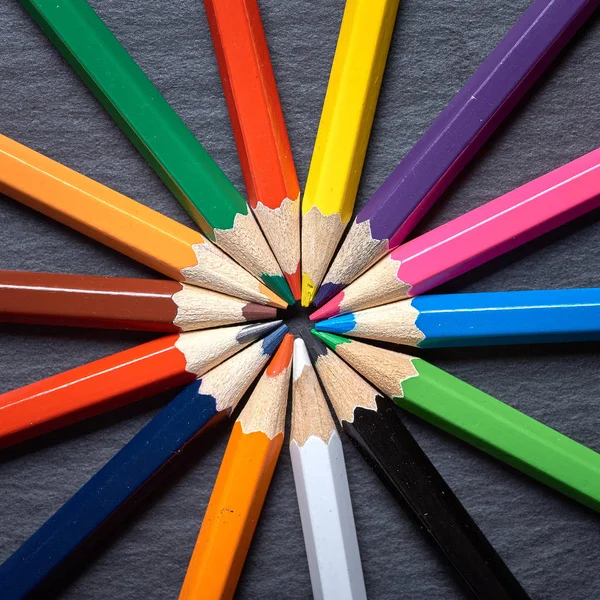 Set of color pencils in shape of sun on grey wooden background. — Stock Photo, Image