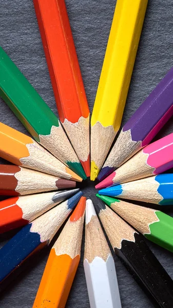 Set of color sharpened pencils in shape of sun on grey wooden background. — Stock Photo, Image