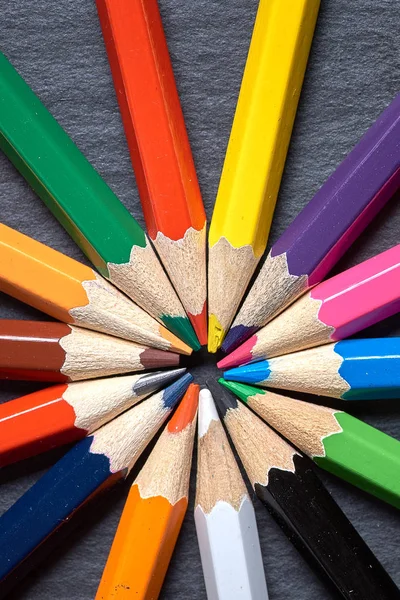 Ensemble de crayons de couleur aiguisés rapprochés en forme de soleil sur fond de bois gris . — Photo