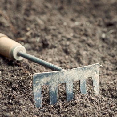 Kullanılan kirli metal bahçe kültivatör toprak arka planda closeup. Bulanıklıkta arka plan.