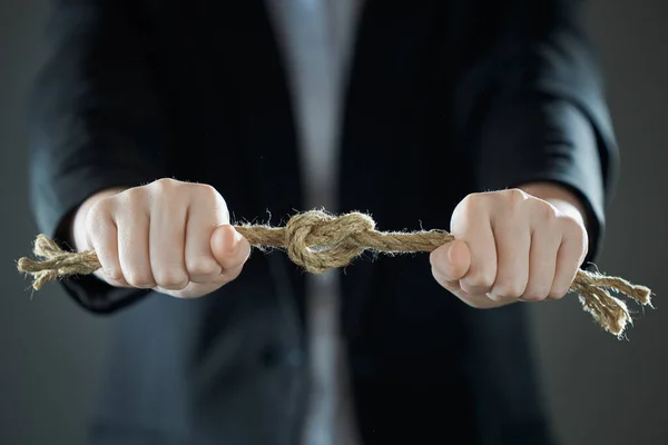 Horizontal shot of businessman\'s hands tighten the rope knot against background of suit in blur. People and business concept.