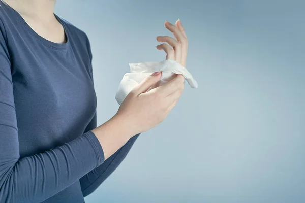 Horizontal shot of girl cleaning her hands by using white antibacterial napkin on gray background.