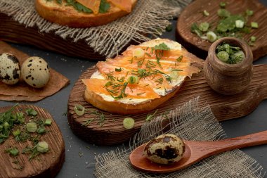 Tahtada peynir ve alabalık sandviçi. Kırmızı balıklı, bıldırcın yumurtalı ve yeşillikli diyet kahvaltı sandviçi..