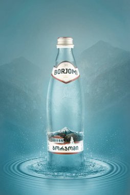Soğuk maden suyu şişesi Borjomi 'nin dikey görüntüsü. Dağların arka planında bulanıklık var. Gürcistan 'ın güneyindeki bir tatil köyünde üretildi..