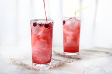 İki bardak buzlu ve siyah üzümlü soğuk kırmızı limonata beyaz arka planda bulanık..