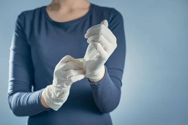 Horizontal shot of girl puts on white rubber gloves. The concept of virus protection.