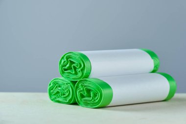 Gri arkaplanda kopya alanı olan üç rulo yeşil eko çöp torbasının yatay görüntüsü.