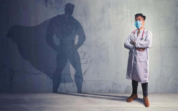 Brave Doctors with his shadow of superhero on the wall. Concept of powerful man