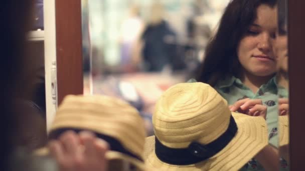 Porträtt av leende brunett försöker på en sommar hatt i en butik — Stockvideo