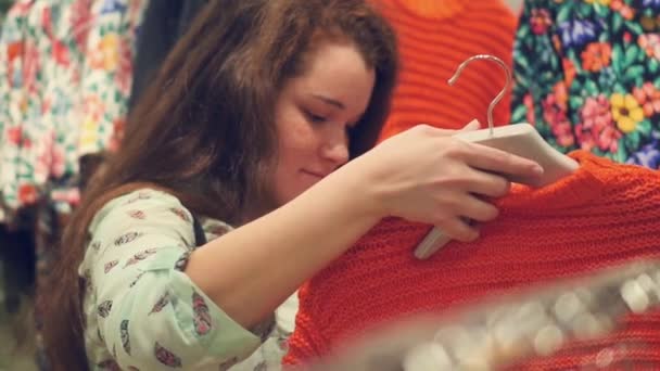 Uma jovem mulher na loja escolher roupas quentes de inverno — Vídeo de Stock