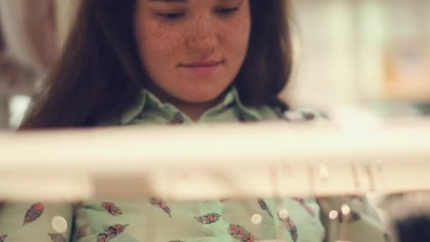 Uma jovem mulher na loja escolher roupas quentes de inverno — Vídeo de Stock