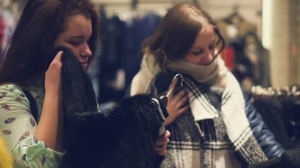 Zwei junge Frauen kaufen im Geschäft ein und wählen warme Winterkleidung — Stockvideo