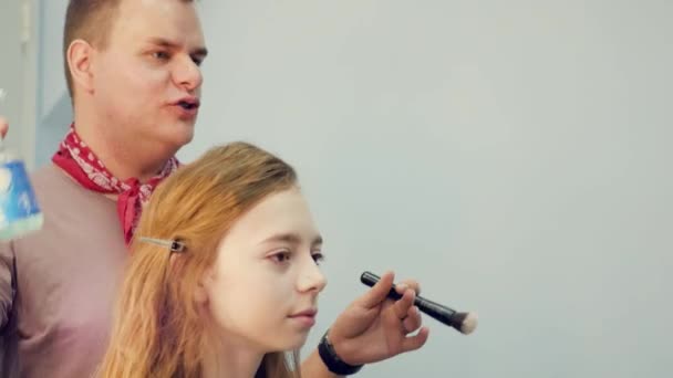 En manlig make-up artist sätter på make-up en ung kvinna. Befälhavaren berättar om makeup för en grupp flickor. Mästarklass för make-up artister. — Stockvideo