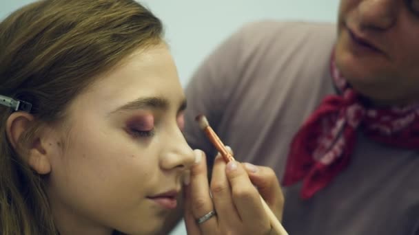 Un maquillador masculino maquilla a una joven. El maestro cuenta sobre el maquillaje para un grupo de chicas. Master class para maquilladores . — Vídeos de Stock