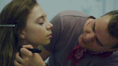 Erkek makyöz makyaj genç bir kadın koyar. Asıl makyaj hakkında bir grup kız söyler. Makyaj sanatçıları için ana sınıfı.