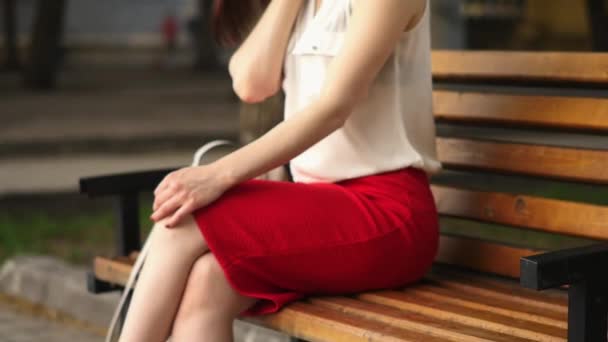 美丽的年轻女子神秘地微笑着, 坐在夏日公园的长凳上。户外妇女肖像. — 图库视频影像