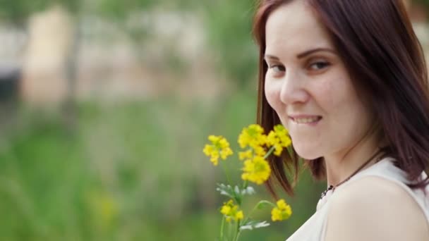 Portret kobiety uśmiechający się na zewnątrz. Żółte kwiaty w rękach kobiet — Wideo stockowe