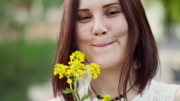 Porträtt av en leende kvinna utomhus. Gula blommor i händerna på kvinnor — Stockvideo