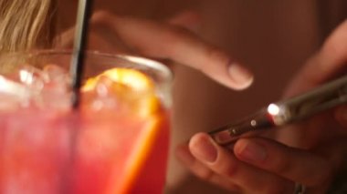 Bir akıllı telefon elinde güzel bir kadınla bir kokteyl barda içecekler.