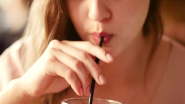 A beautiful woman with a smartphone in her hand drinks a cocktail at the bar — Stock Video