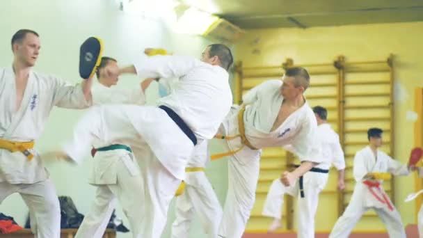 Rusia, Novosibirsk, 15 Agustus 2018 Sekelompok orang berlatih stroke karate di dalam ruangan. Pelatihan ketahanan dalam karate — Stok Video