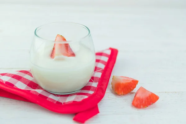 Original flavor yogurt with fresh strawberry in clear glass on w