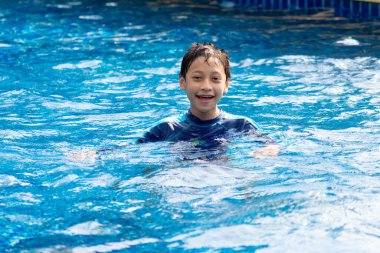 Küçük çocuk havuzda yüzüyor.