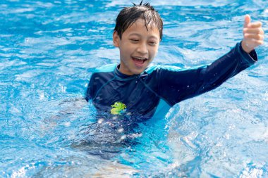 Küçük çocuk havuzda yüzüyor.