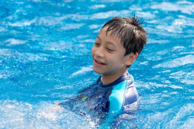 Küçük çocuk havuzda yüzüyor.
