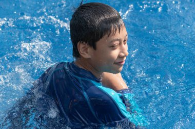 Küçük çocuk havuzda yüzüyor.