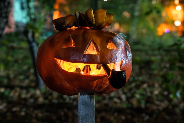 Sonriente calabaza símbolo de la fiesta de halloween sosteniendo una pipa para fumar tabaco en la boca. Jack fuma una pipa. — Foto de Stock