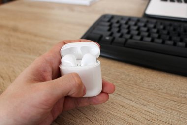 Beyaz kulaklık kutusuyla ofiste tutan adam