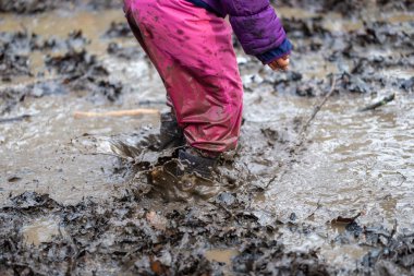 Bir çamur birikintisinde oynayan genç çocuk