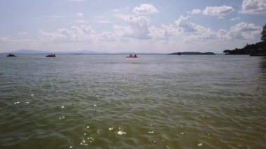Lago Trasimeno üzerinde pedalos ve kano kullanan tatilciler, Sualzo plajı açıklarında, Umbria, İtalya