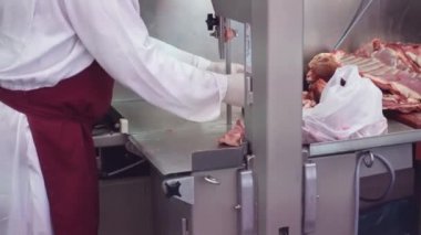 Yetenekli erkek kasap testereyle et kesiyor.