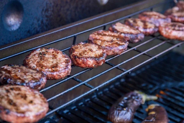 Barbecued beef burgers on a barbecue warming rack — ストック写真
